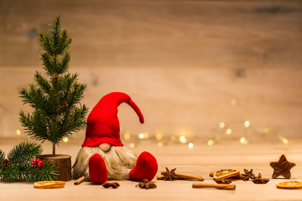 Artigos de Natal: miniatura de uma árvore de Natal à esquerda e o boneco de um Papai Noel sentado ao seu lado