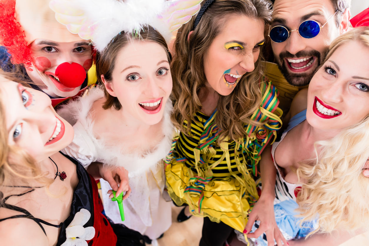 Fantasia de Carnava: foto com seis pessoas, homens e mulheres, cada um vestido com uma fantasia diferente. Todos estão sorrindo para a câmera.