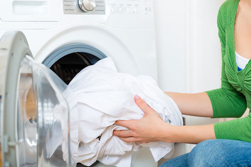Máquina de Lavar - Lavadora - Mulher colocando a roupa para lavar